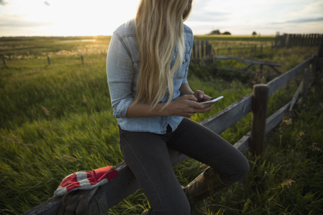 Woman on farm reading email on mobile phone