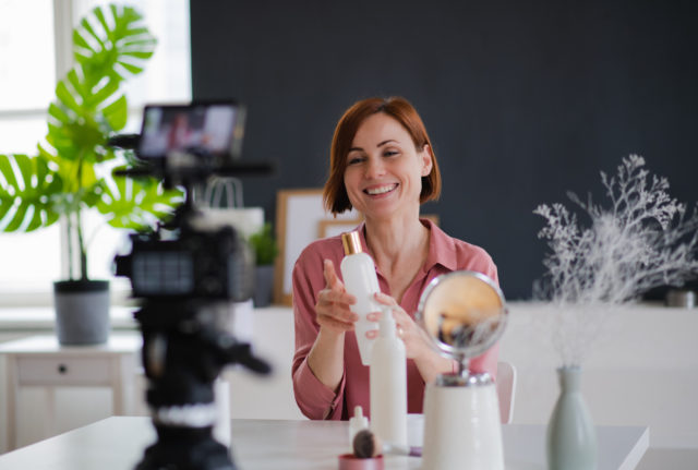 Female podcaster sitting at the table, talking on camera.