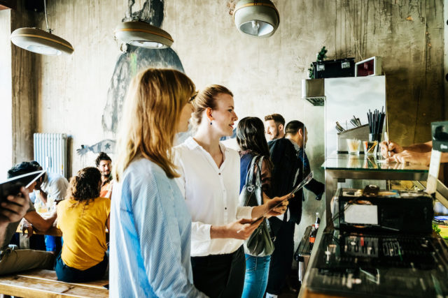 Some people ordering food at the counter in a busy, trendy burger restaurant.