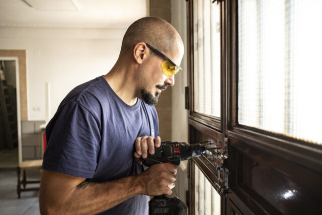 Locksmith changes a lock at home with a drill